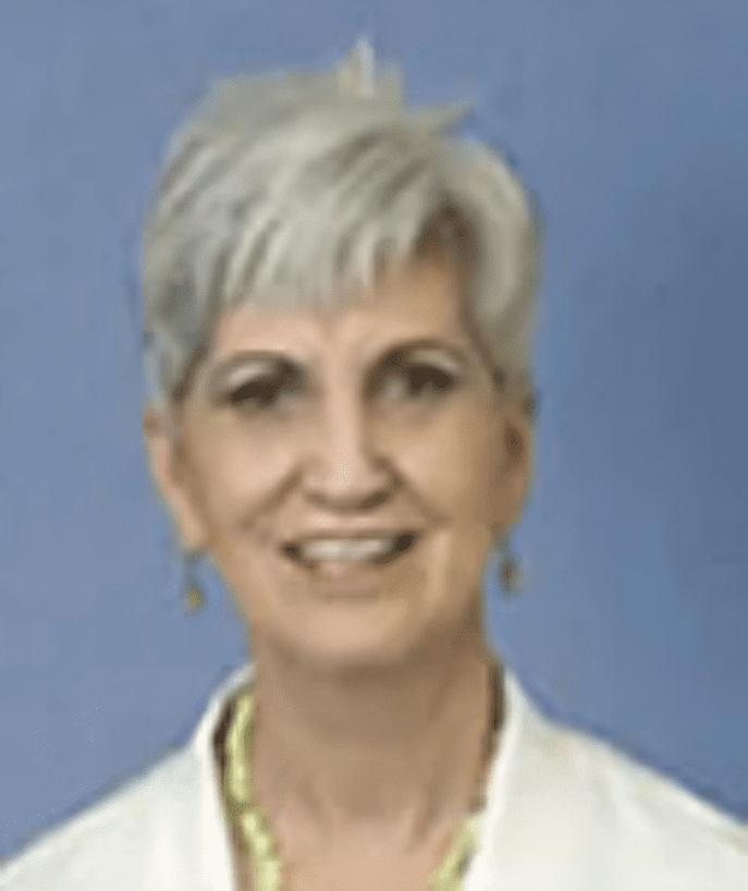 A woman with white hair is smiling for the camera.