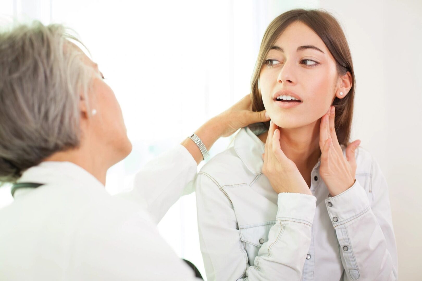 A woman is looking at her face in the mirror.