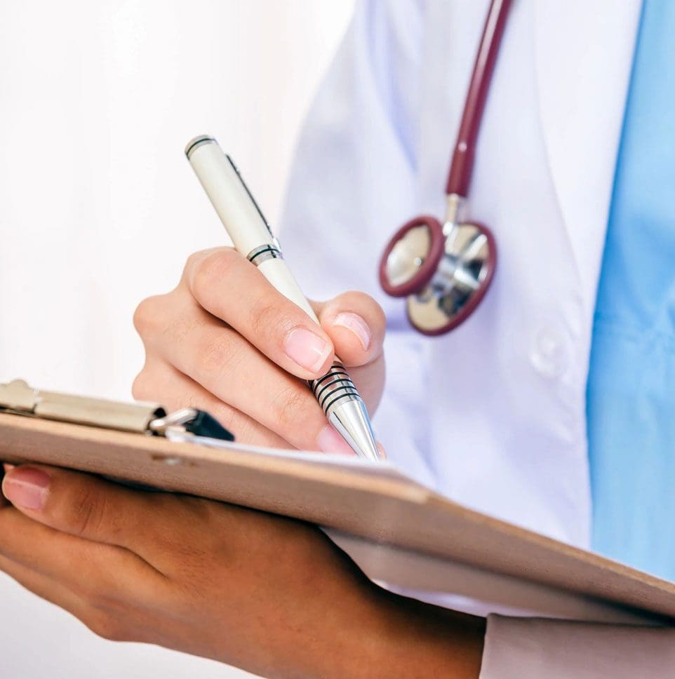 A doctor writing on a notepad with a stethoscope around his neck.